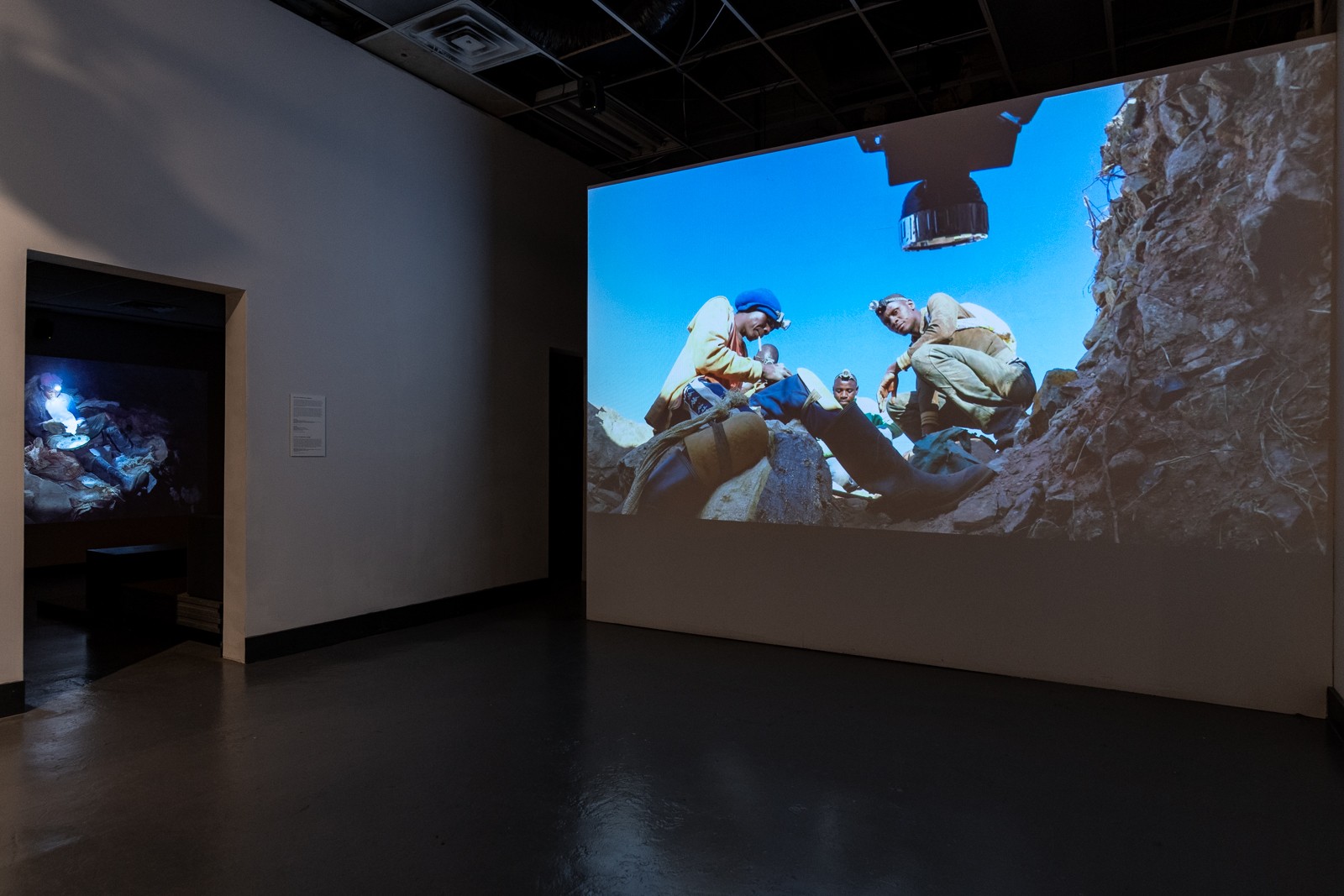 Installation view of 'The Zama Zama Project,' with video projection of miners making offerings to spirits